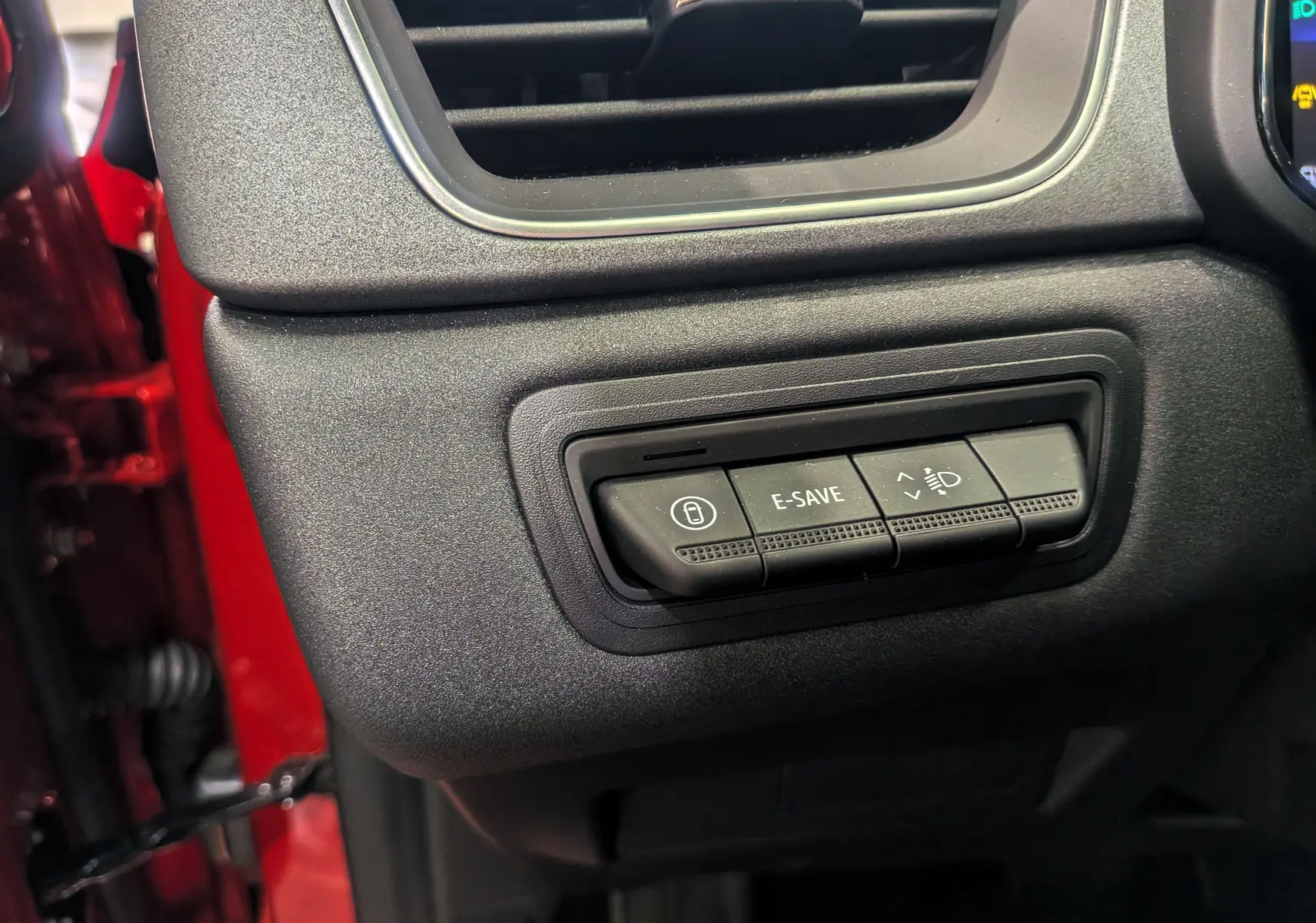Gros plan sur les commandes E-SAVE et réglage des phares du tableau de bord du Renault Captur rouge Flamme 2025.