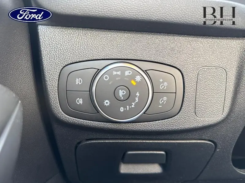 Gros plan sur le bouton de réglage des phares avec commandes d'éclairage dans l'habitacle de la Ford Focus rouge.
