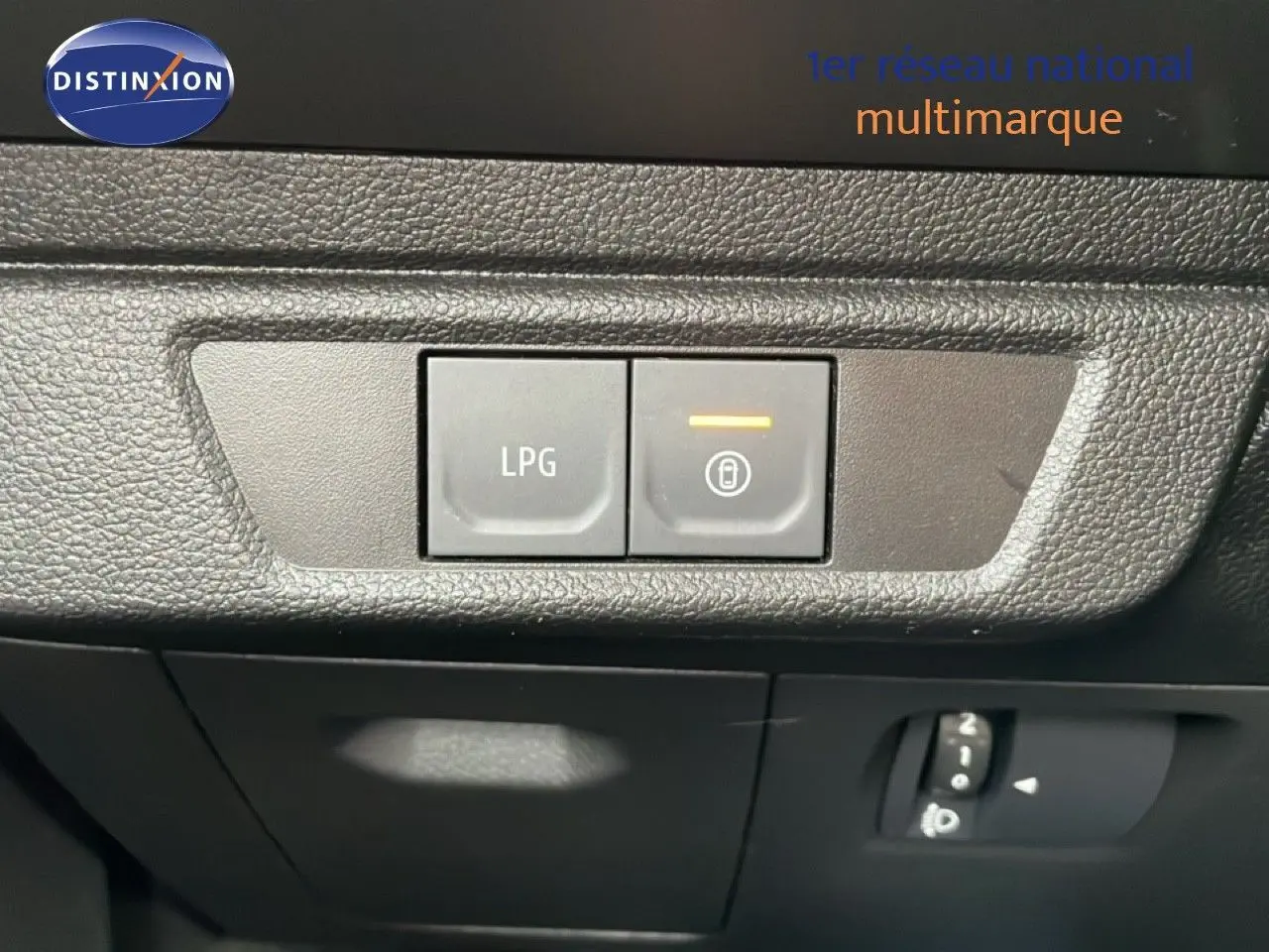 Gros plan sur les boutons de commande LPG et verrouillage intérieur du tableau de bord d'un Dacia Jogger gris schiste métal.
