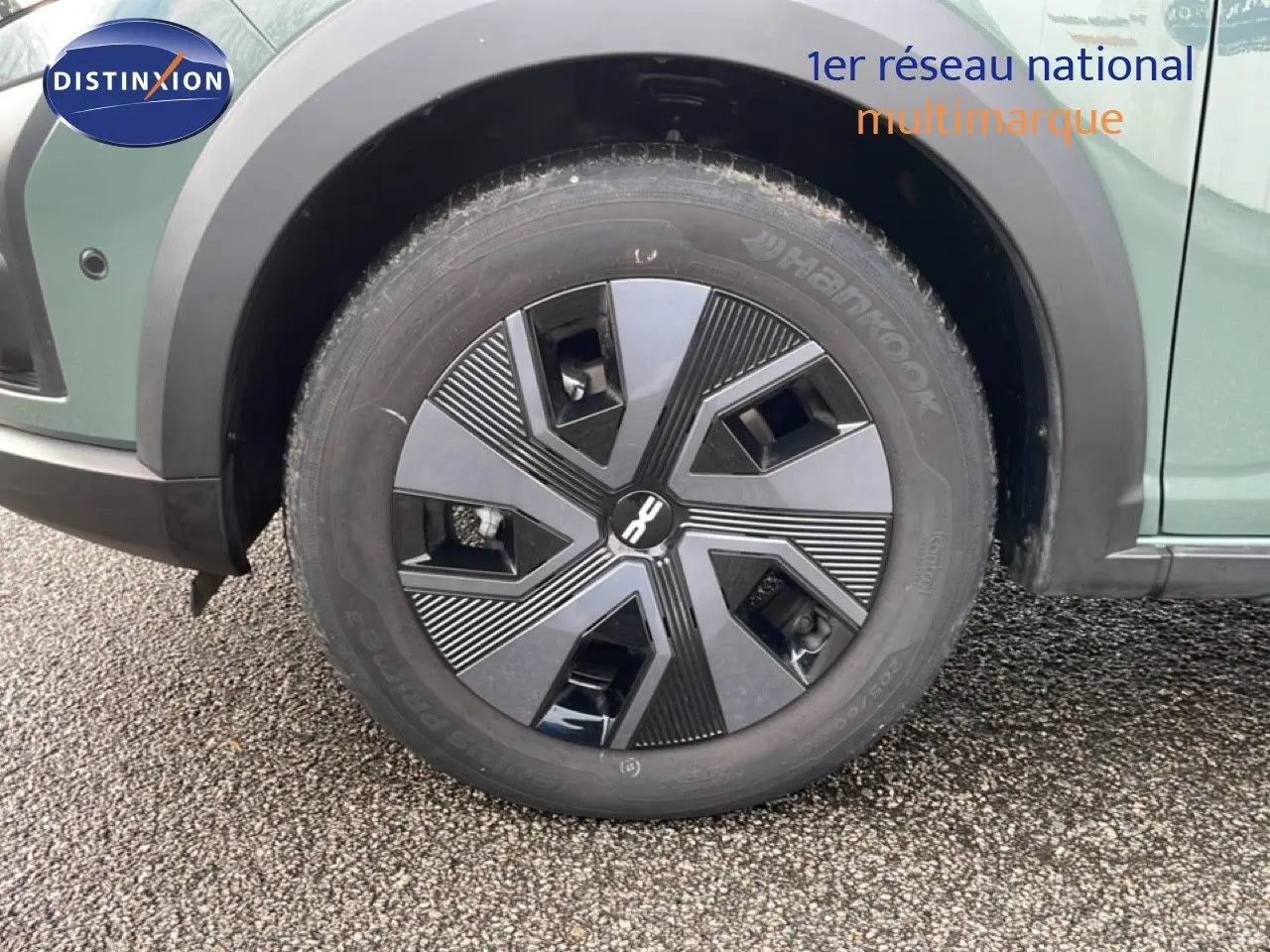 Gros plan sur la roue avant gauche d’un Dacia Jogger gris schiste métal avec jante au design géométrique noir et gris.