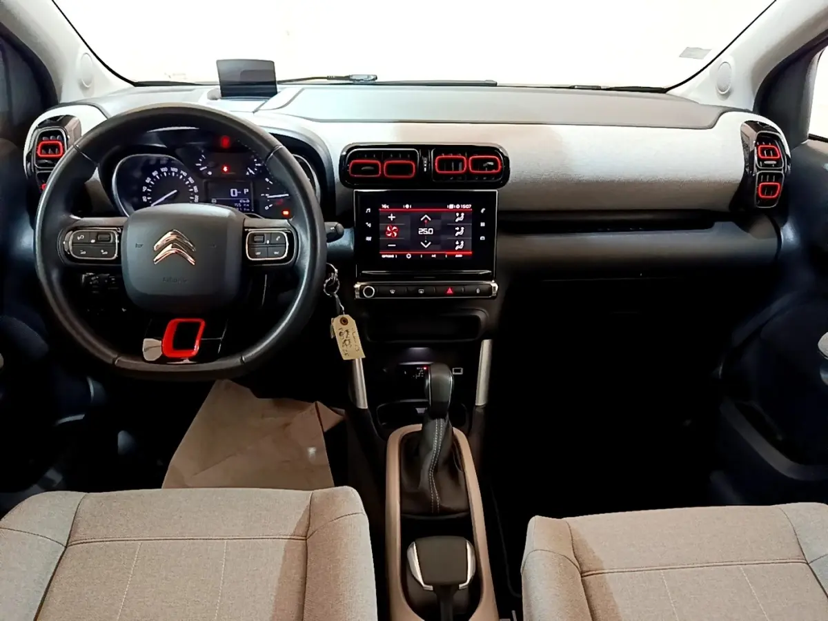 Vue intérieure avant de la Citroën C3 Aircross 2020, tableau de bord gris clair avec touches rouges et volant cuir noir.
