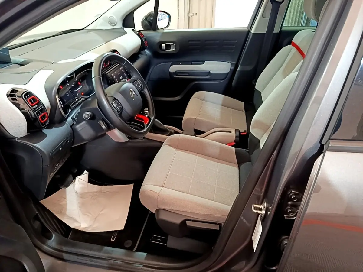 Vue intérieure côté conducteur de la Citroën C3 Aircross gris foncé, sièges tissu beige et volant cuir multifonctions.