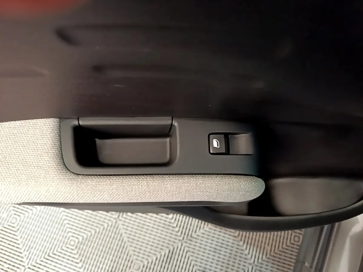 Gros plan sur la poignée intérieure et le bouton de lève-vitre côté porte avant droit du Citroën C3 Aircross gris foncé.