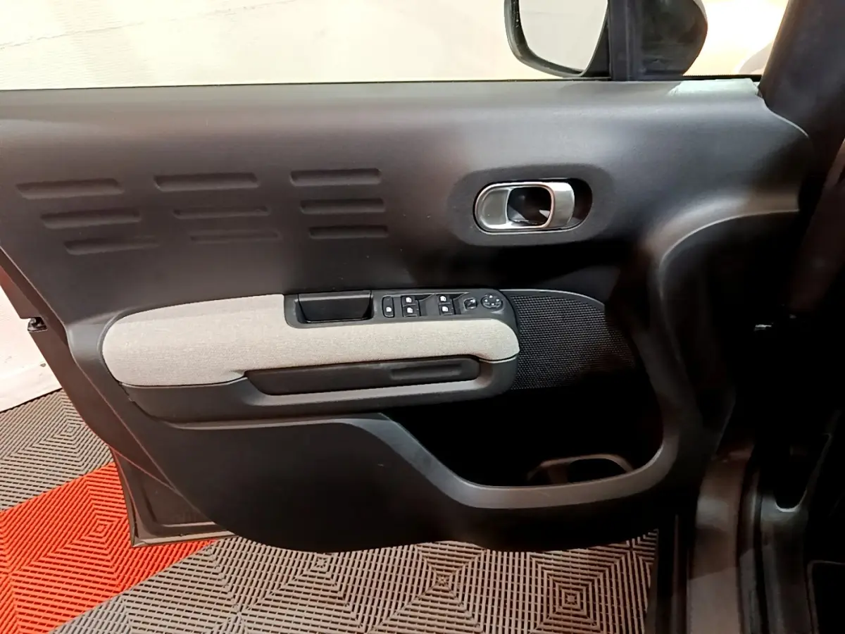 Vue intérieure côté gauche de la porte avant d'une Citroën C3 Aircross 2020 avec accoudoir gris clair et commandes électriques.