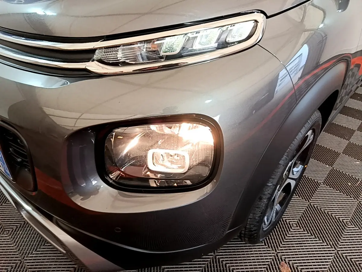 Gros plan sur l'avant droit gris foncé du Citroën C3 Aircross 2020, mettant en valeur ses phares allumés et sa calandre.