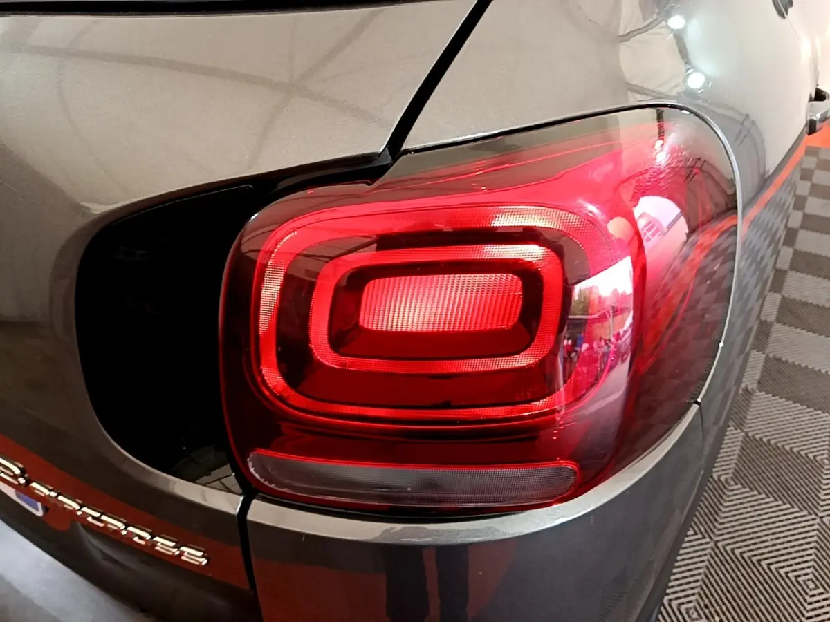 Gros plan sur le feu arrière droit rouge du Citroën C3 Aircross gris foncé, avec logo partiel visible sur le coffre.