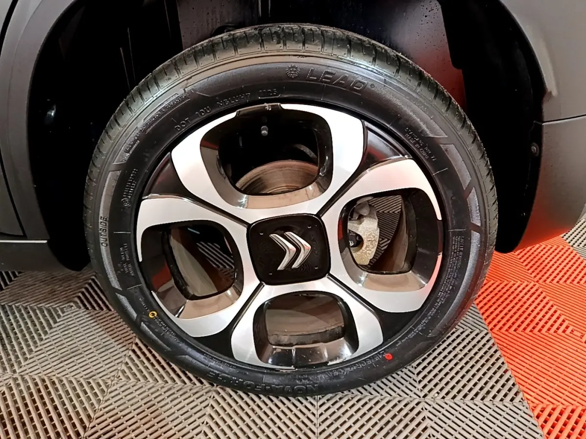 Gros plan sur la roue arrière droite d'une Citroën C3 Aircross gris foncé, avec passage de roue noir mat.