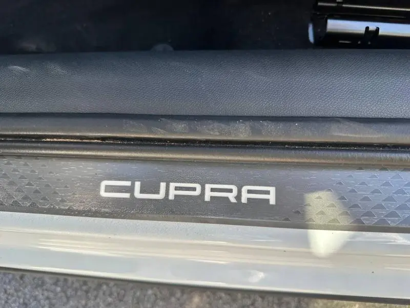 Gros plan sur la plaque de seuil de porte avec logo CUPRA, sur un CUPRA Formentor blanc Nevada métallisé.