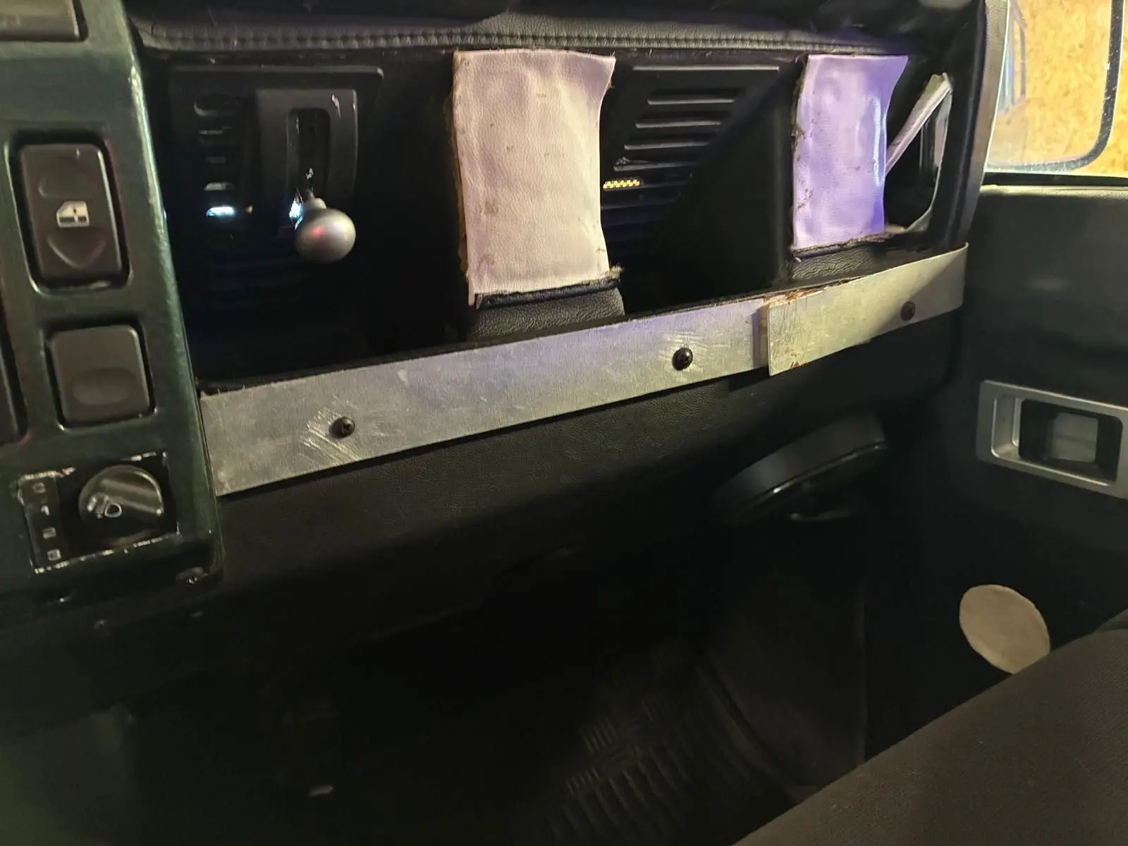 Vue intérieure du tableau de bord du Land Rover Defender 110 vert 2005, mettant en valeur la console centrale et les commandes.