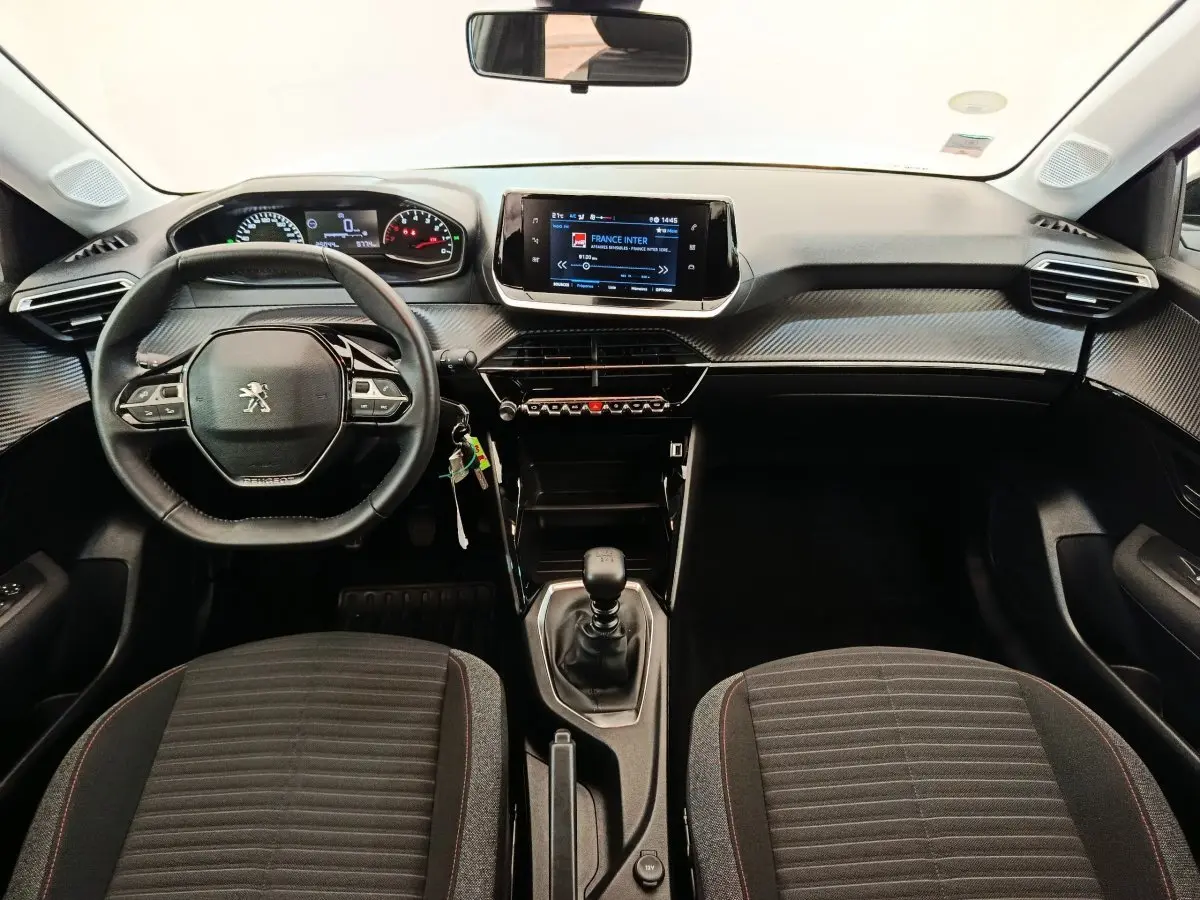Vue intérieure avant du tableau de bord et volant cuir noir de la Peugeot 208 BlueHDi 100 S&S Active 2022.