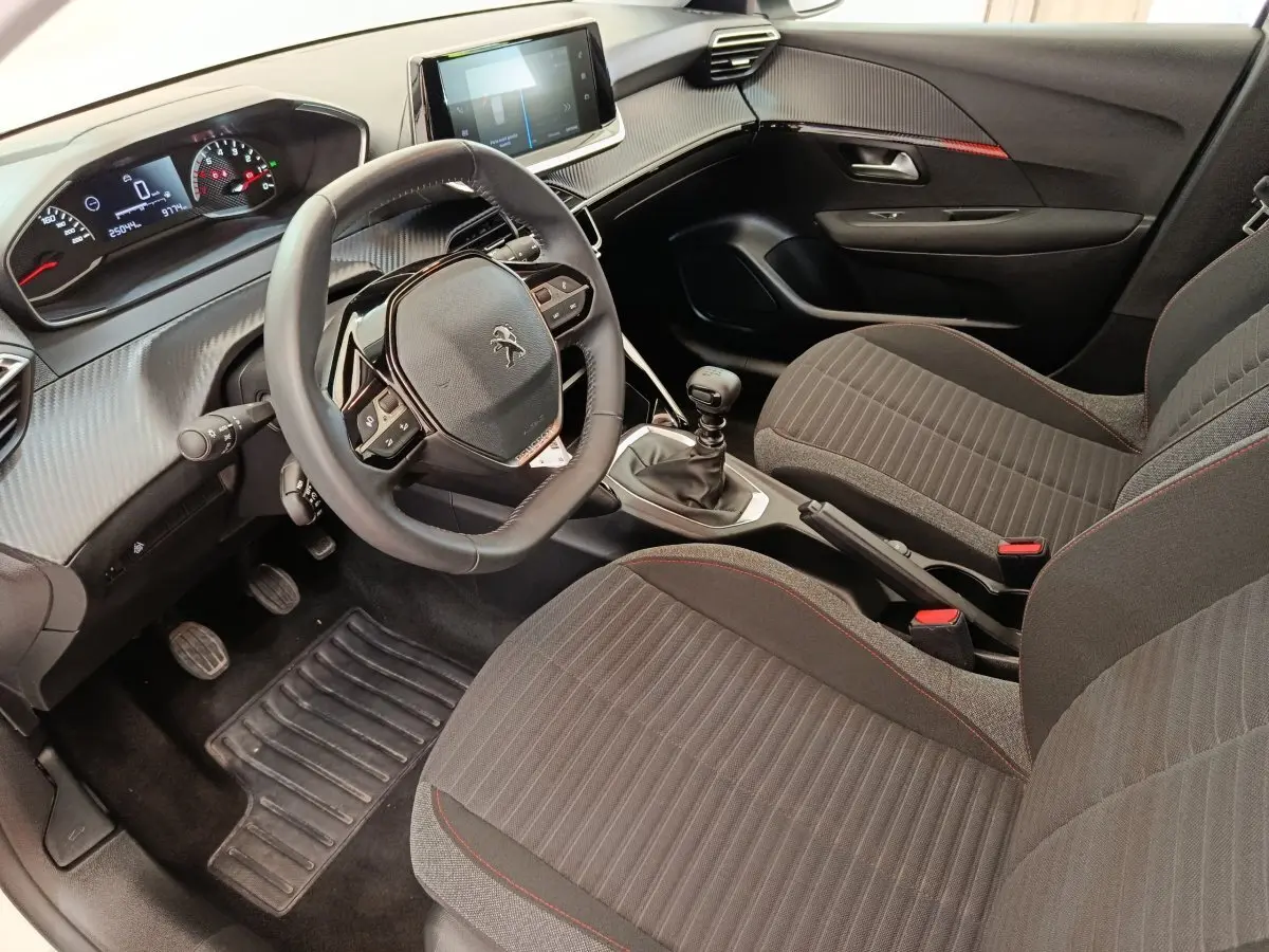 Vue intérieure côté conducteur de la Peugeot 208 2022 avec volant cuir multifonctions et tableau de bord digital.