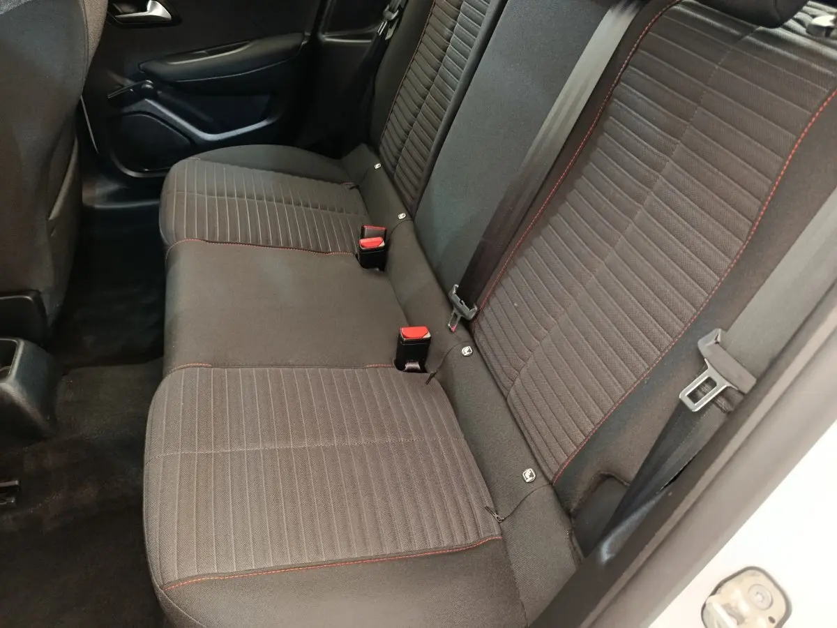 Vue intérieure côté droit sur la banquette arrière noire avec surpiqûres rouges du Peugeot 208 blanc 2022.