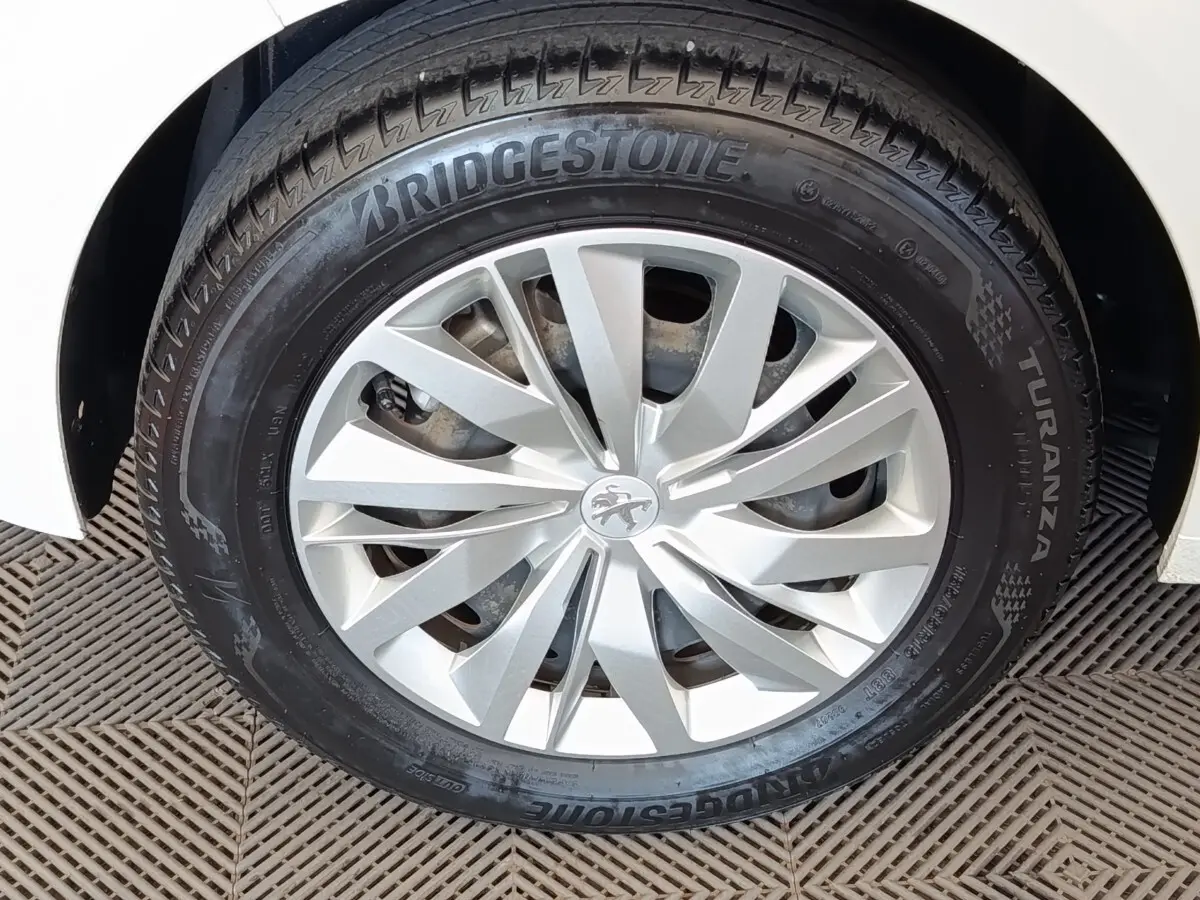 Gros plan sur la roue avant gauche d’une Peugeot 208 blanche, avec jante argentée et pneu Bridgestone Turanza.