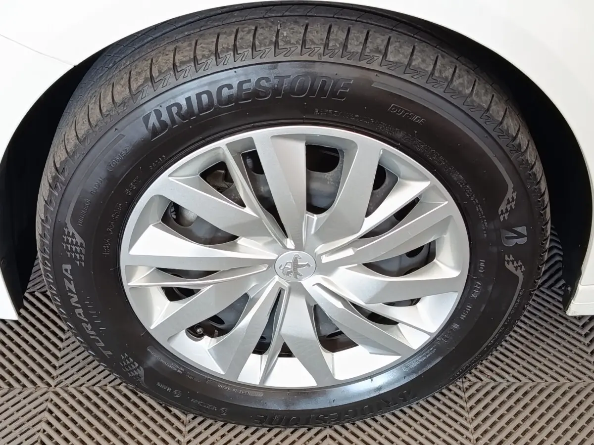 Gros plan sur la roue avant droite d’une Peugeot 208 blanche avec jante alliage et pneu Bridgestone.