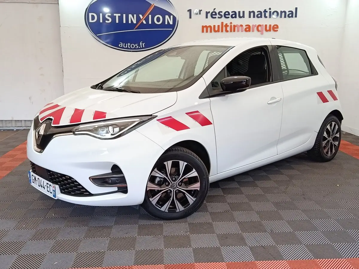 Renault ZOE blanche vue 3/4 avant droit avec bandes rouges distinctives sur capot et ailes.