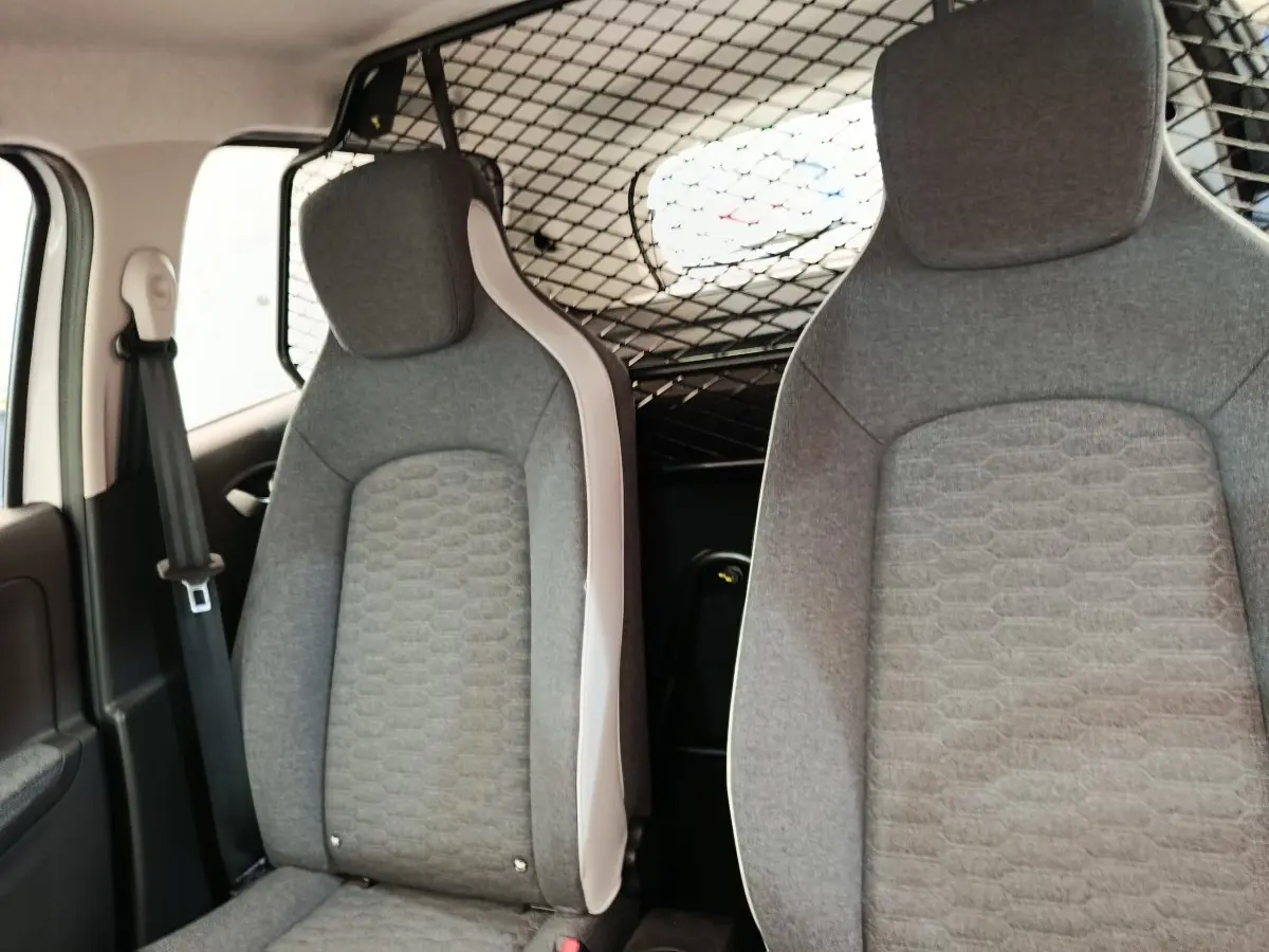 Vue intérieure avant des sièges gris de la Renault ZOE électrique avec séparation grillagée derrière les sièges.