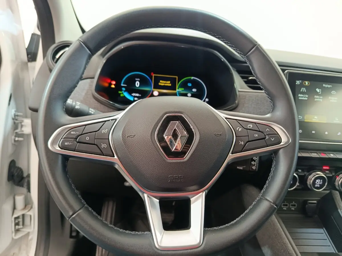 Vue rapprochée du volant en cuir synthétique noir de la Renault ZOE blanche 2023 avec tableau de bord digital.