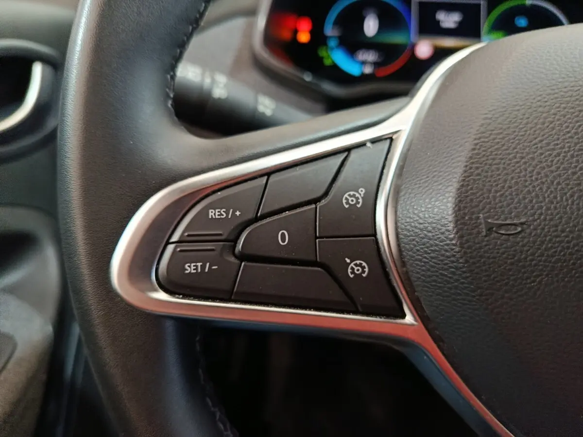 Gros plan sur le volant cuir synthétique de la Renault ZOE blanc, avec commandes multifonctions visibles.