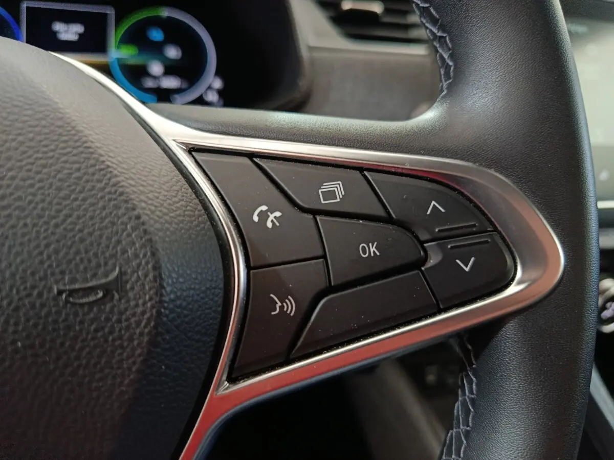 Gros plan sur les commandes multifonctions du volant en cuir synthétique noir de la Renault ZOE blanche 2023.