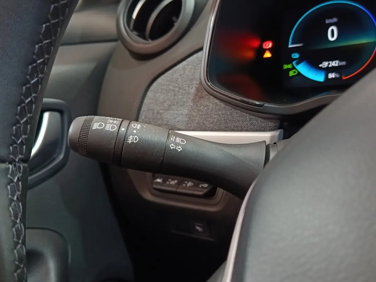 Gros plan sur la manette de commande des phares et clignotants côté gauche du tableau de bord de la Renault ZOE blanche.