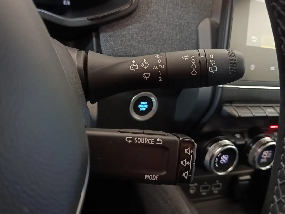 Gros plan sur les commandes au volant et bouton démarrage d’une Renault ZOE blanche, intérieur moderne et fonctionnel.