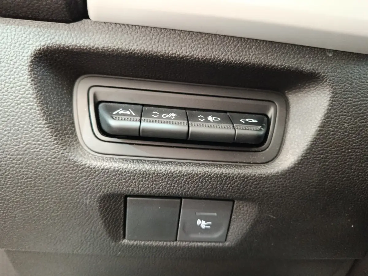 Gros plan sur les boutons de commande noirs intégrés dans le tableau de bord noir d'une Renault ZOE blanche.