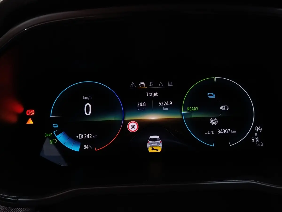 Tableau de bord numérique de Renault ZOE blanc, affichage multifonctions avec vitesse, autonomie et alertes visibles.