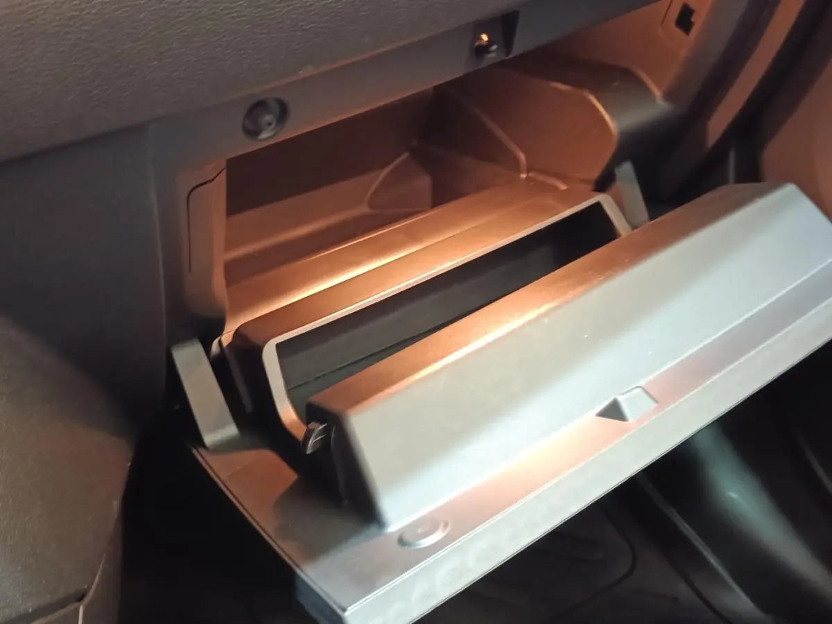 Gros plan sur la boîte à gants ouverte de la Renault ZOE blanche, intérieur noir avec éclairage doux.