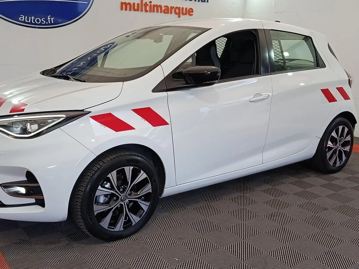 Vue de profil droit d'une Renault ZOE blanche 2023 avec bandes rouges diagonales sur ailes avant et arrière.