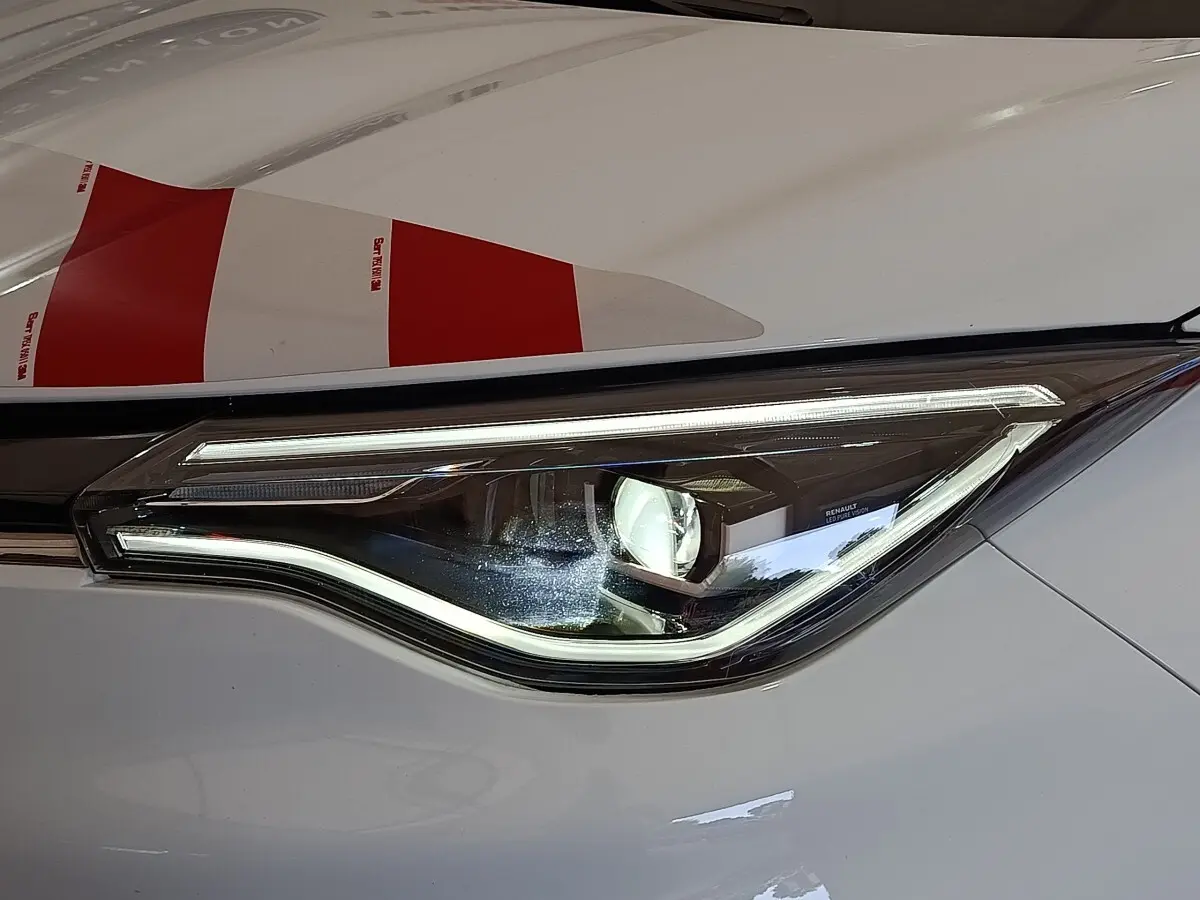 Gros plan sur le phare avant droit LED de la Renault ZOE blanche, soulignant son design moderne et épuré.