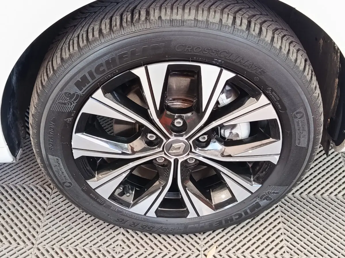 Gros plan sur la roue avant droite d'une Renault ZOE blanche, jante alliage bicolore et pneu Michelin.