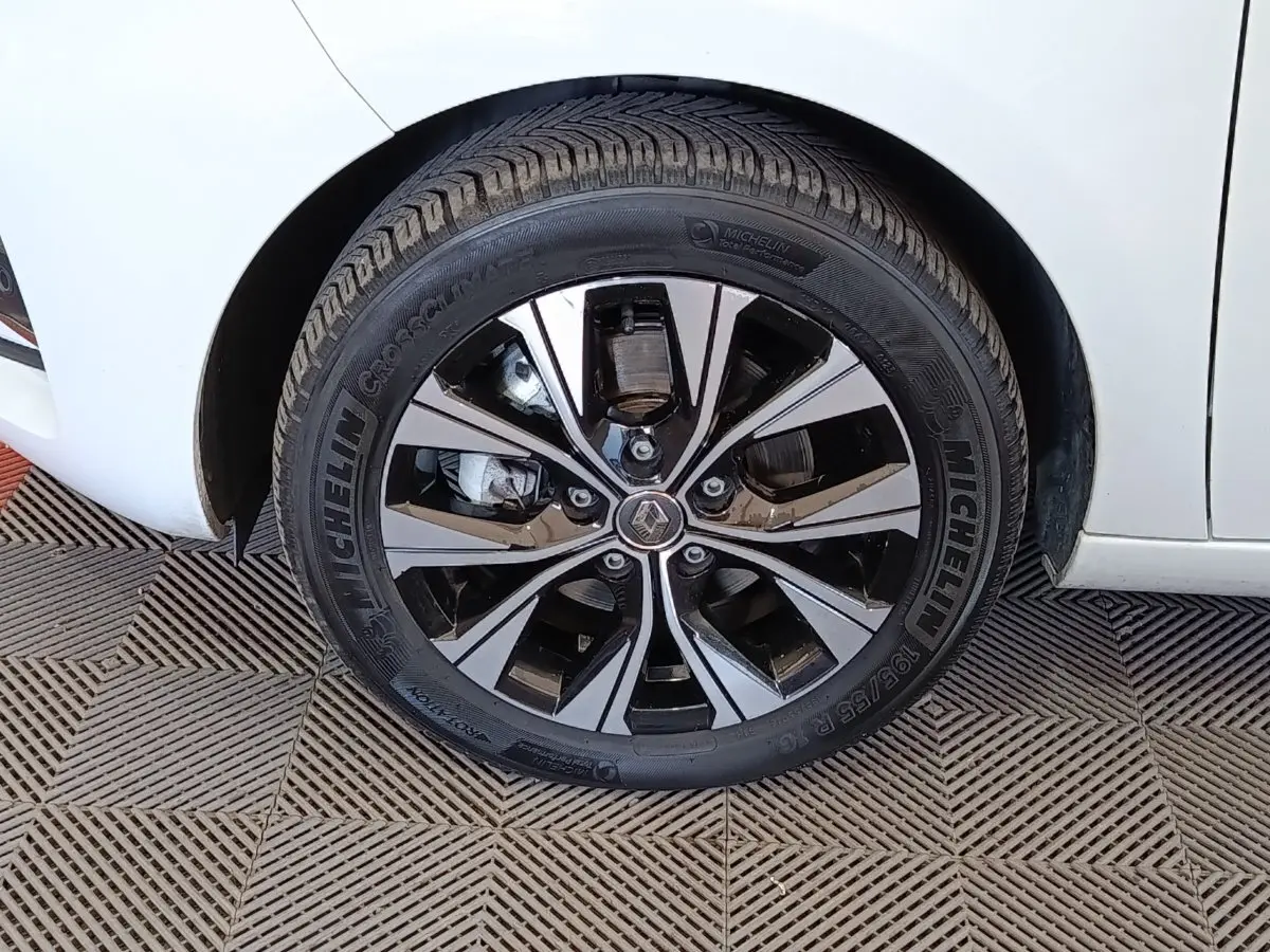 Gros plan sur la roue avant gauche d’une Renault ZOE blanche avec jante alliage bicolore et pneu Michelin.
