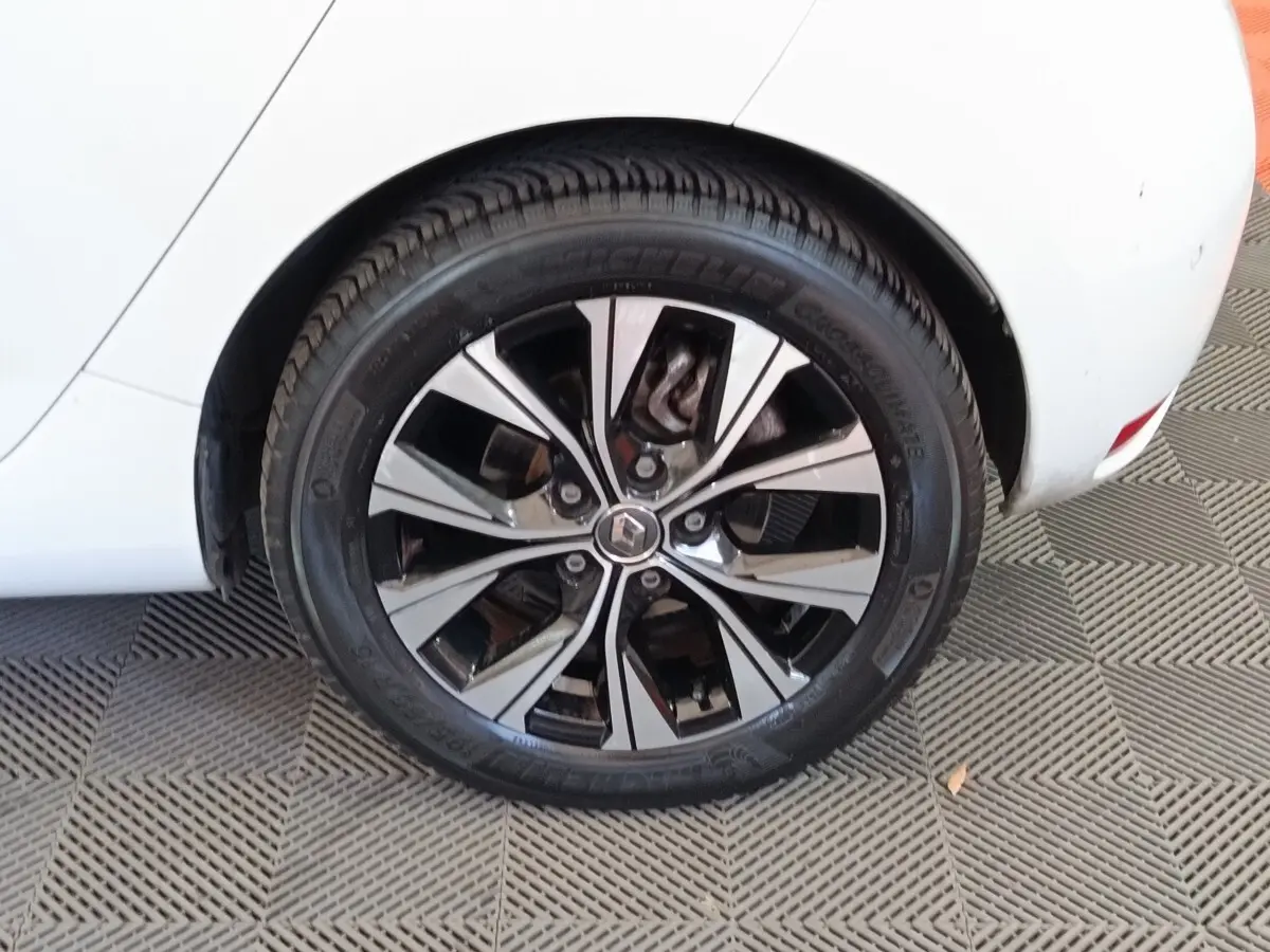 Gros plan sur la roue arrière droite de la Renault ZOE blanche avec jante alliage bicolore et logo Renault central.