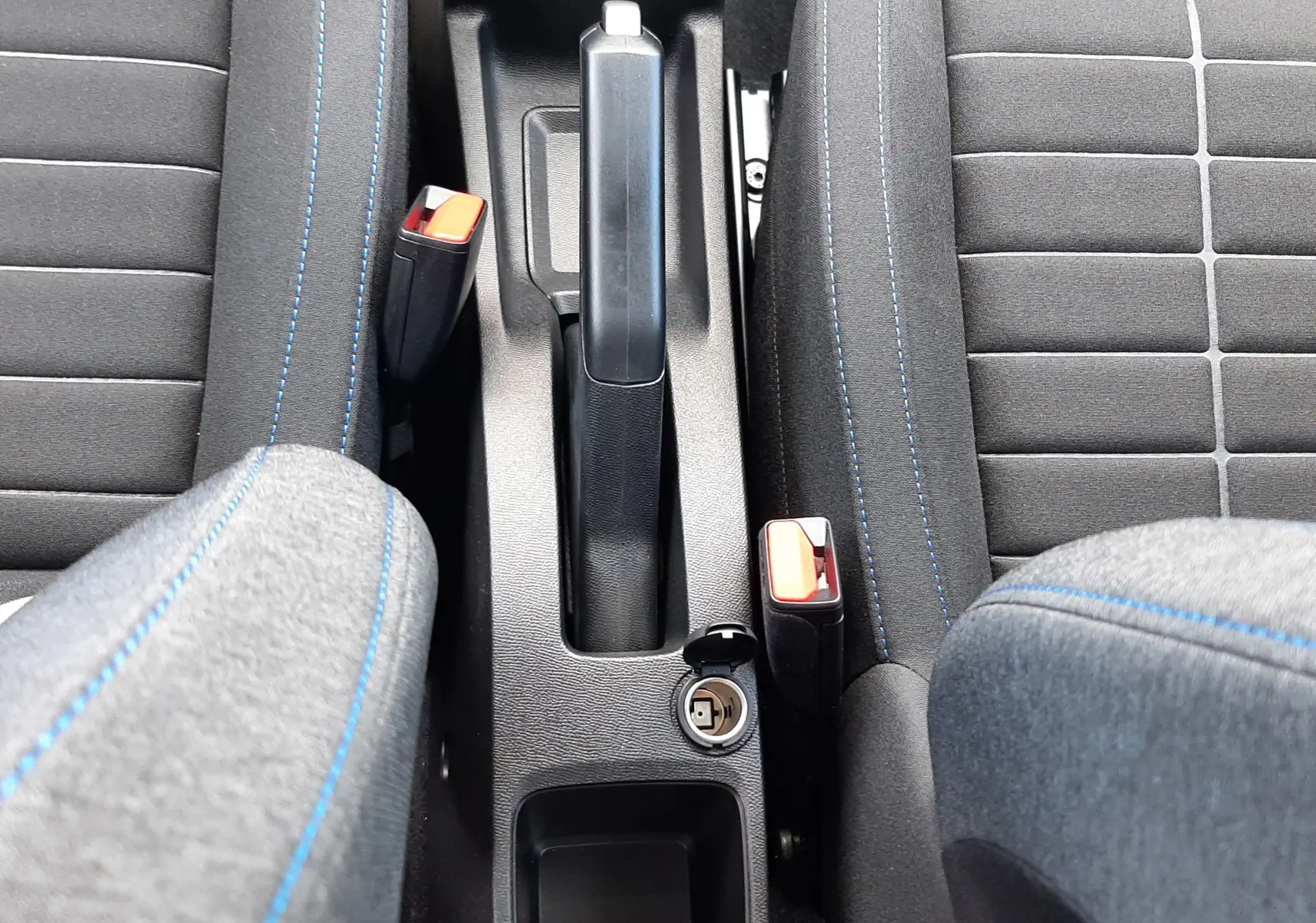 Vue plongeante sur la console centrale et les sièges avant en tissu gris avec surpiqûres bleues d'une Citroën C3 Turbo 100ch Plus 2026.