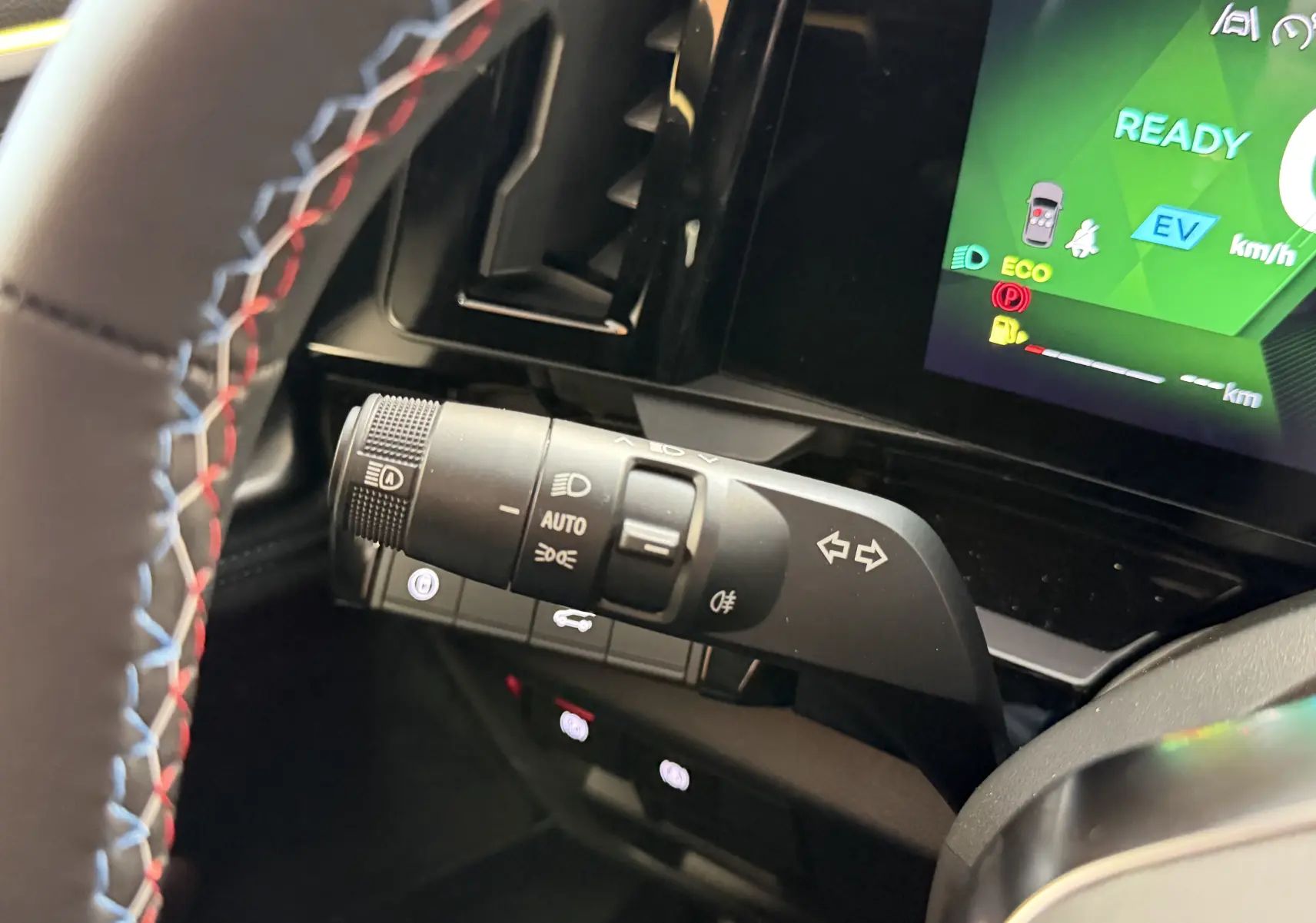 Gros plan sur la commande des feux et clignotants à gauche du volant avec surpiqûres tricolores du volant du Renault Austral E-Tech 2026.