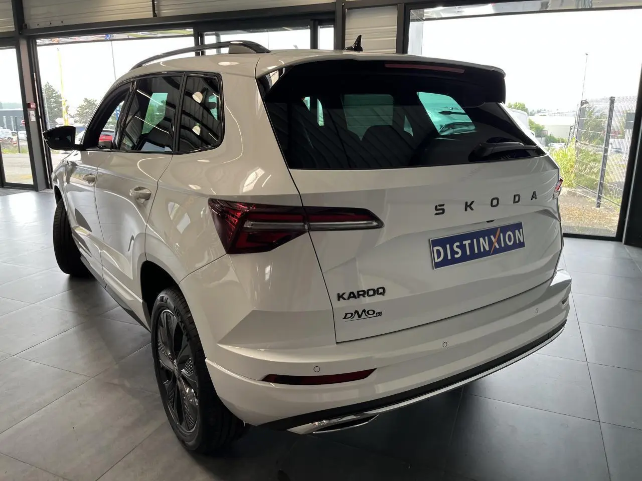 Vue 3/4 arrière droit du SUV blanc SKODA KAROQ 2025 avec feux arrière LED et jantes noires Sportline