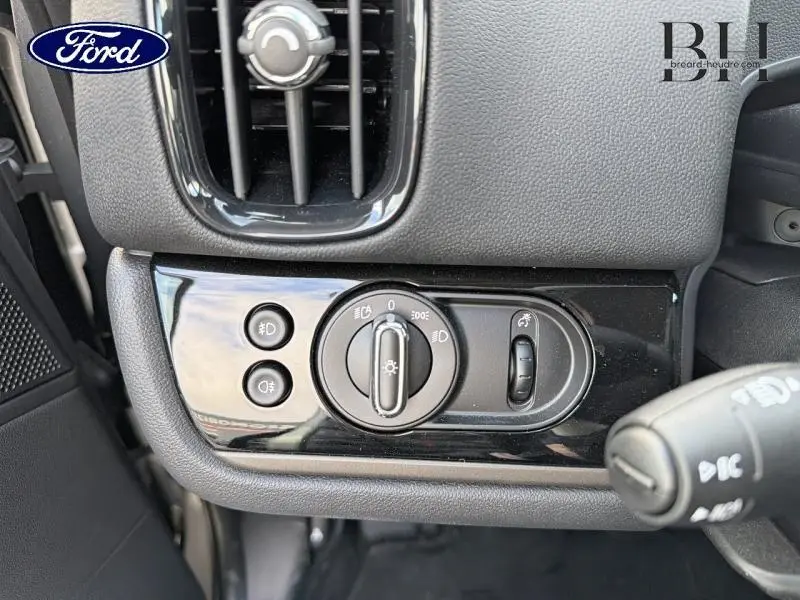 Gros plan sur le panneau de commande des phares du MINI COUNTRYMAN Melting Silver III, côté gauche du tableau de bord.