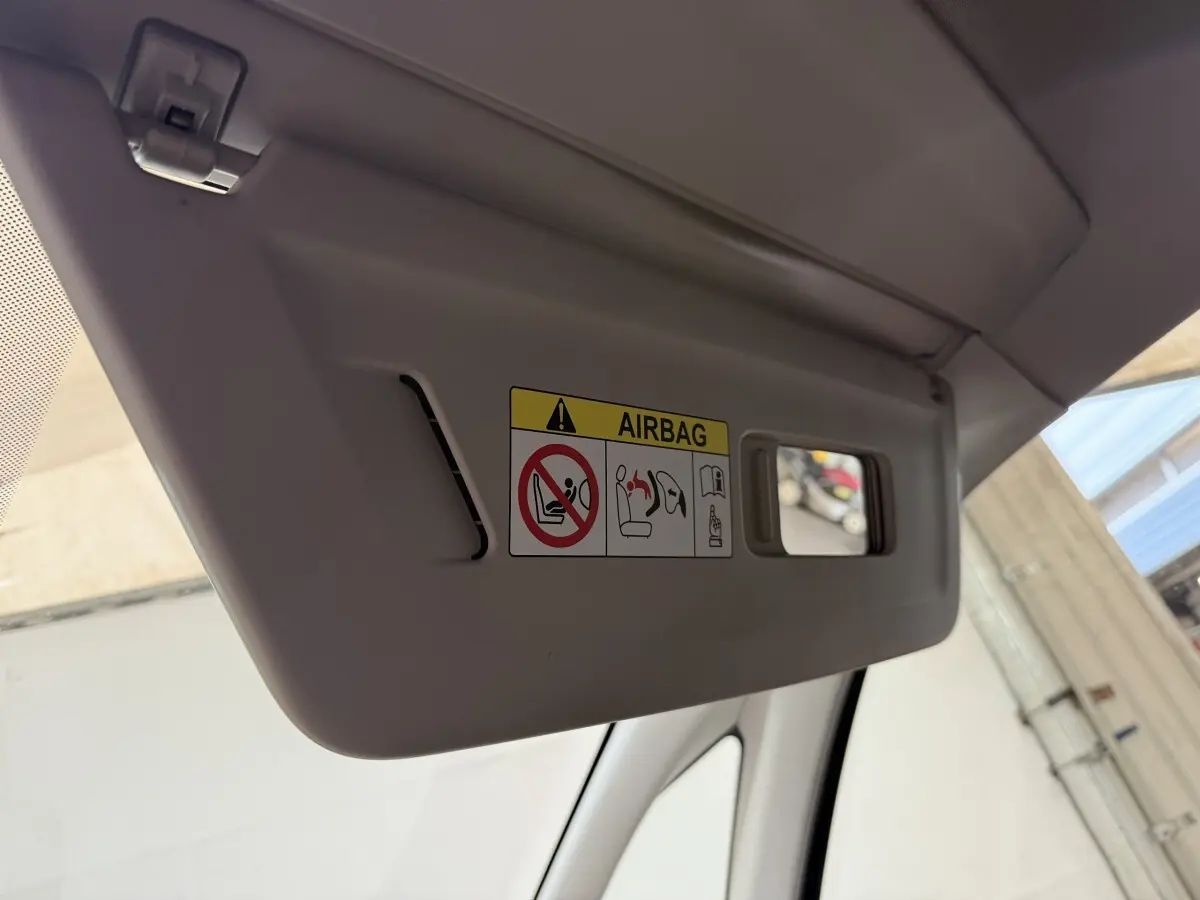 Pare-soleil côté conducteur gris clair avec avertissement airbag et petit miroir intégré, vue intérieure rapprochée.