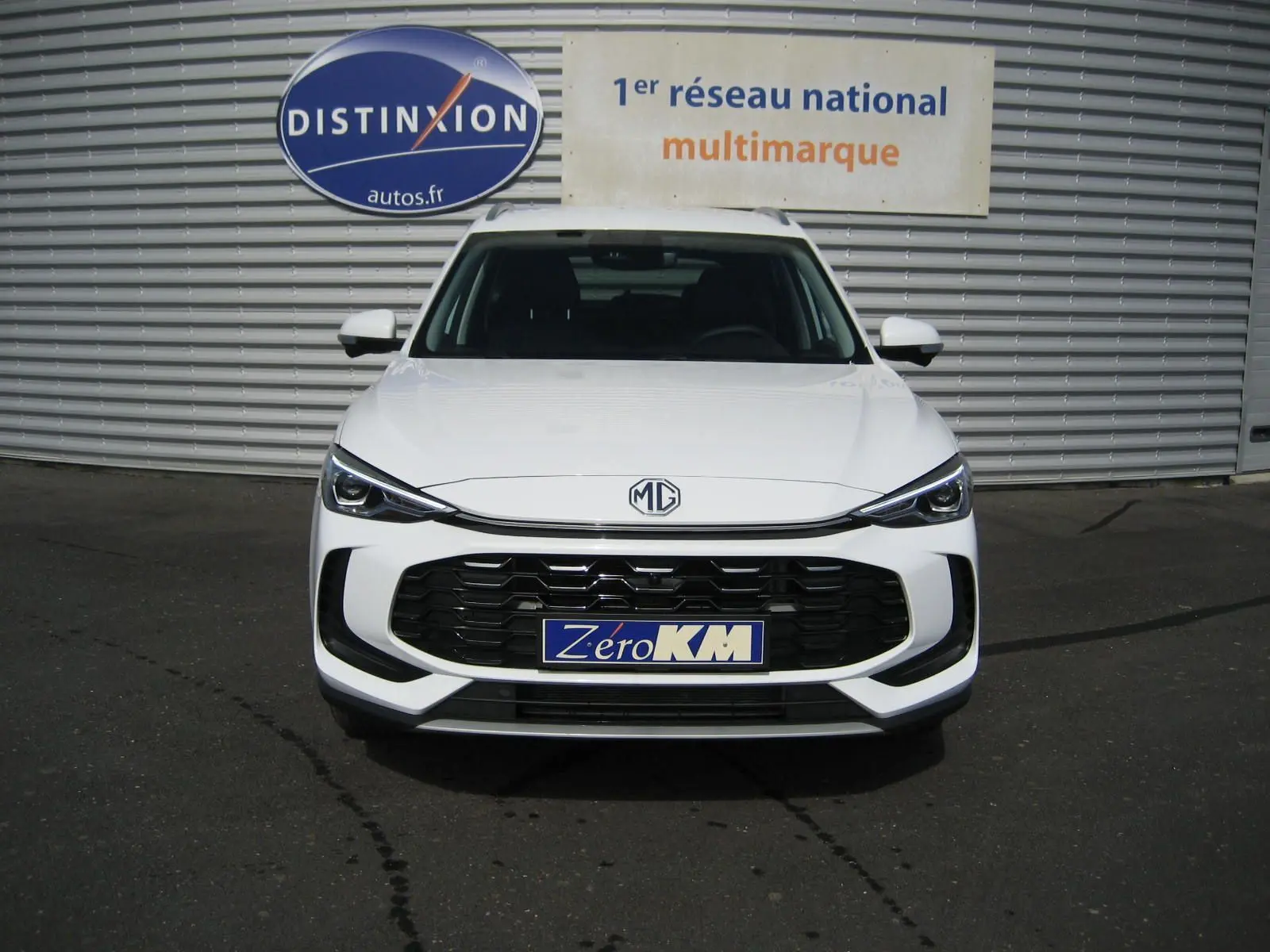 Vue frontale d'un MG ZS 1.5 HYBRID+197 LUXURY blanc avec calandre noire et logo MG centré.