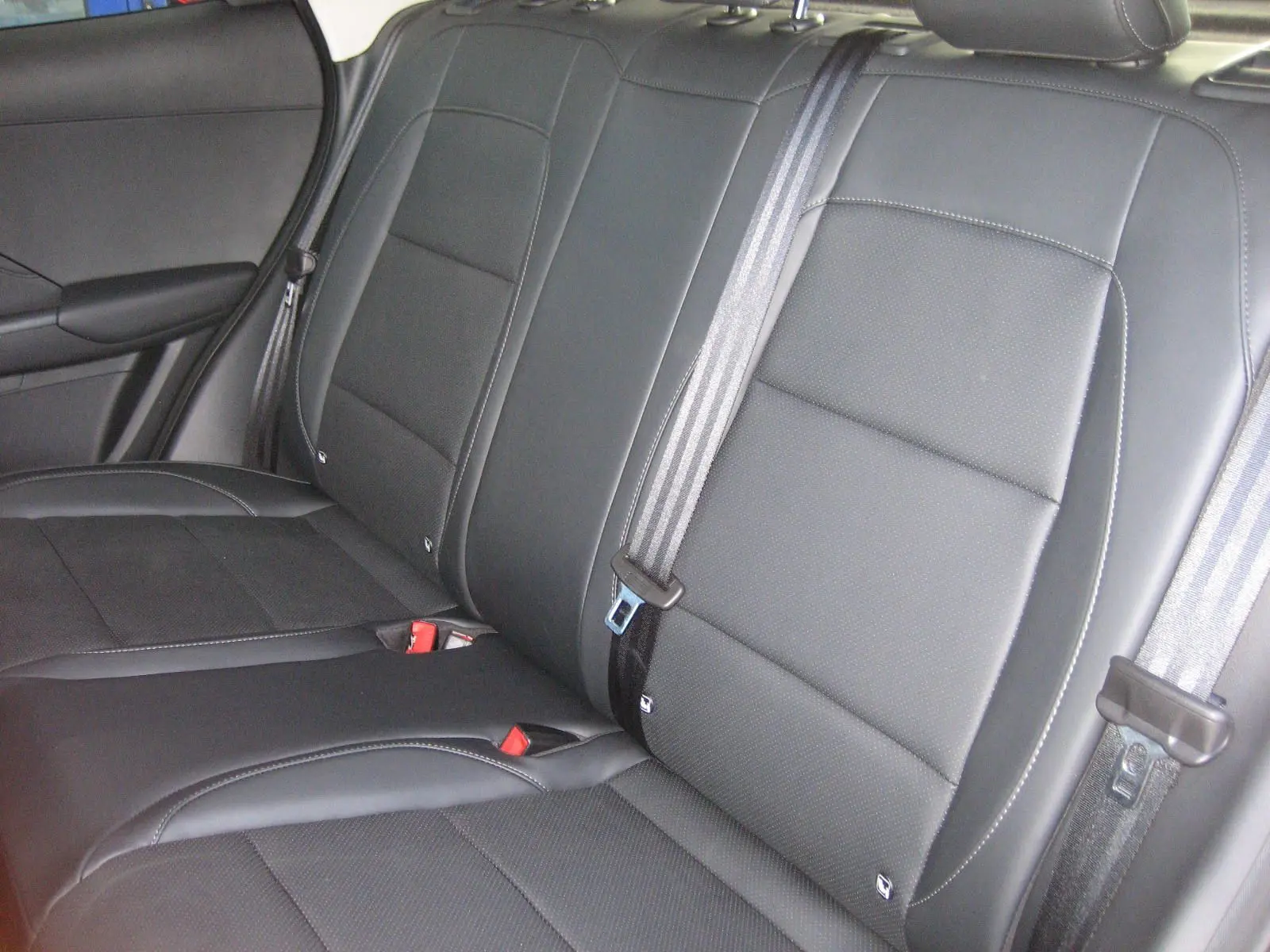Vue rapprochée des sièges arrière en cuir noir du MG ZS 1.5 HYBRID+197 LUXURY, avec ceintures de sécurité visibles.