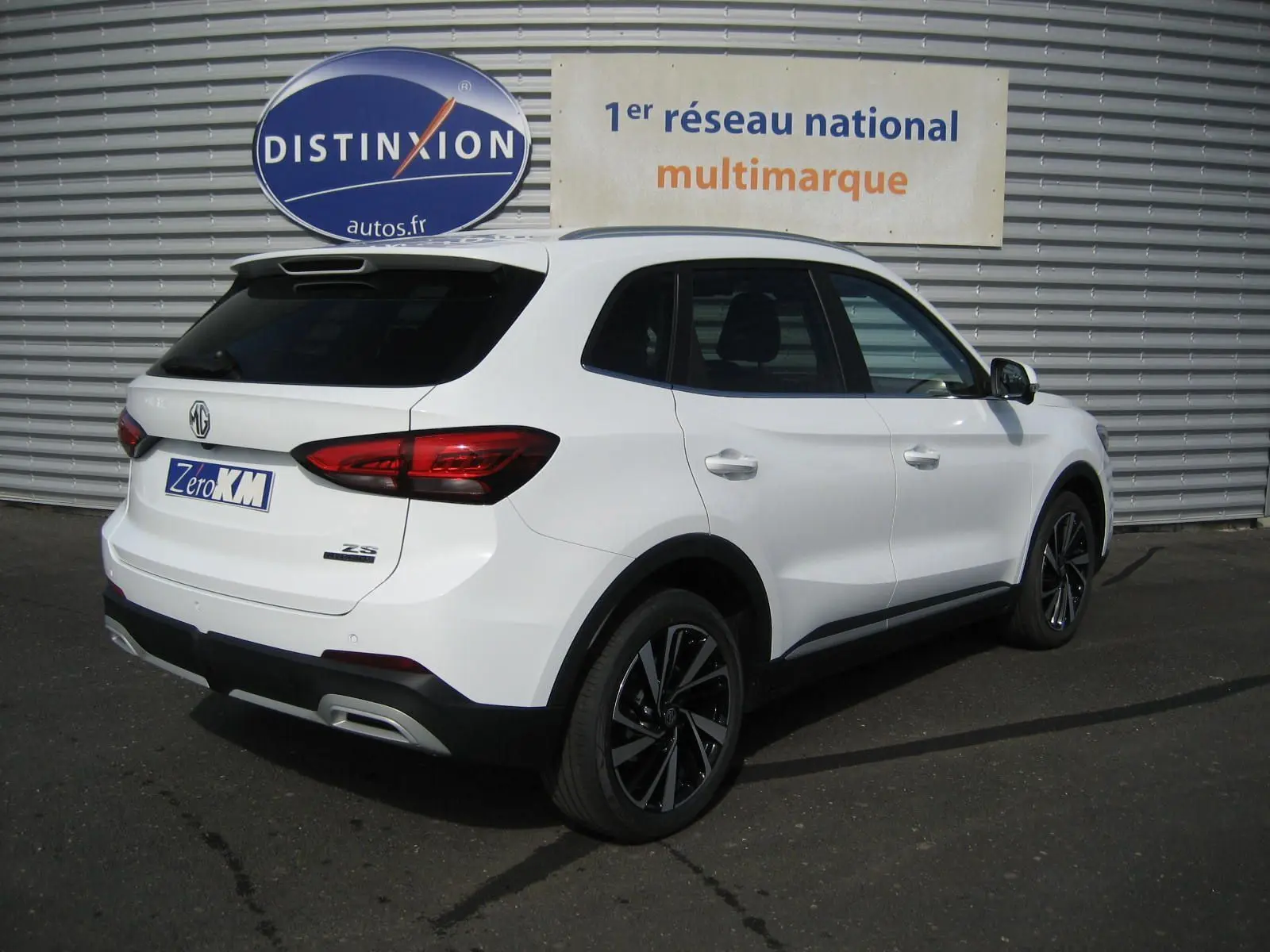 Vue 3/4 arrière droite du SUV blanc MG ZS 1.5 HYBRID+197 LUXURY avec jantes noires et feux arrière LED.