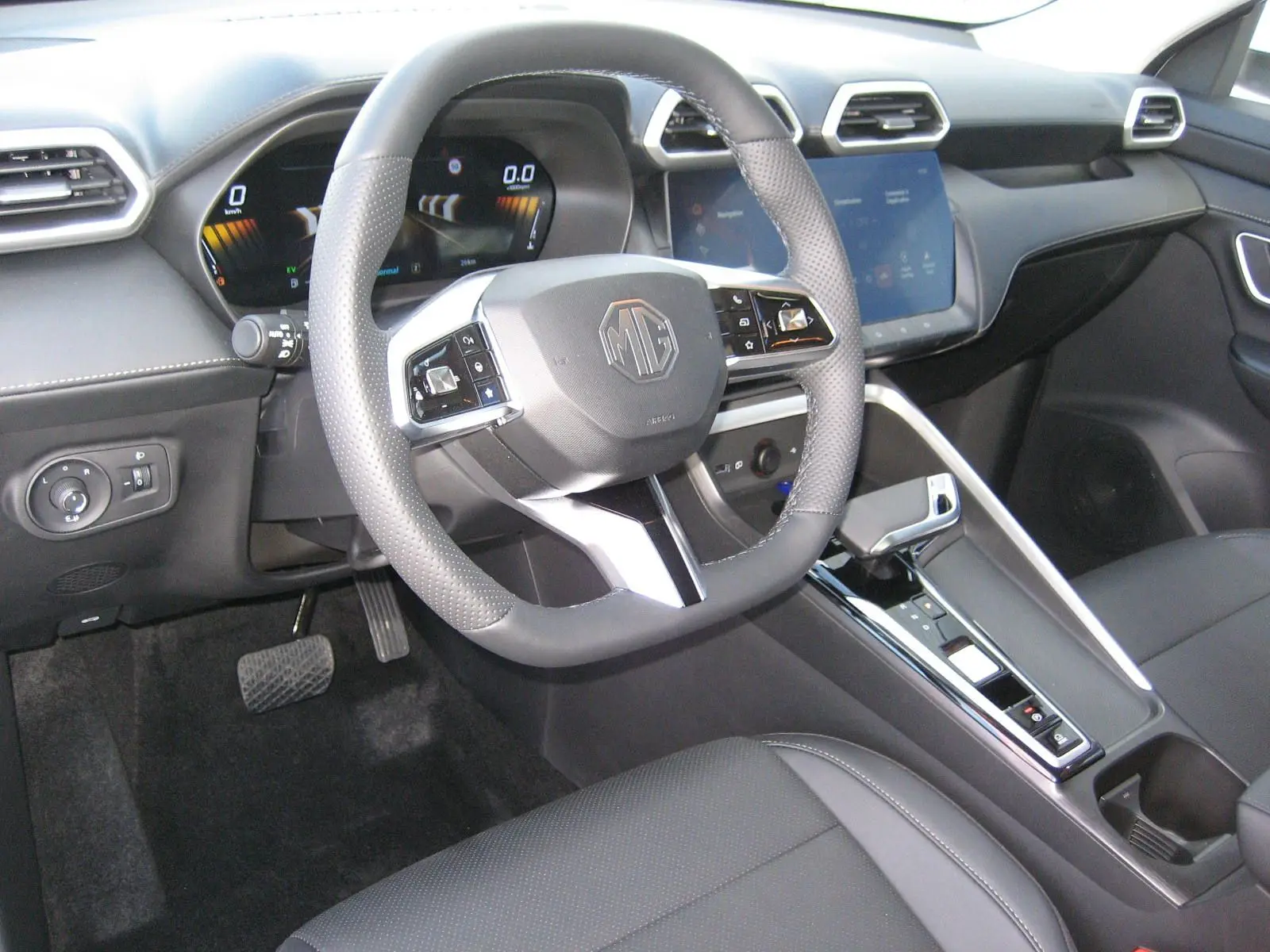 Vue intérieure centrée sur le volant et la console centrale du MG ZS 1.5 HYBRID+197 LUXURY avec sellerie noire et écran tactile.