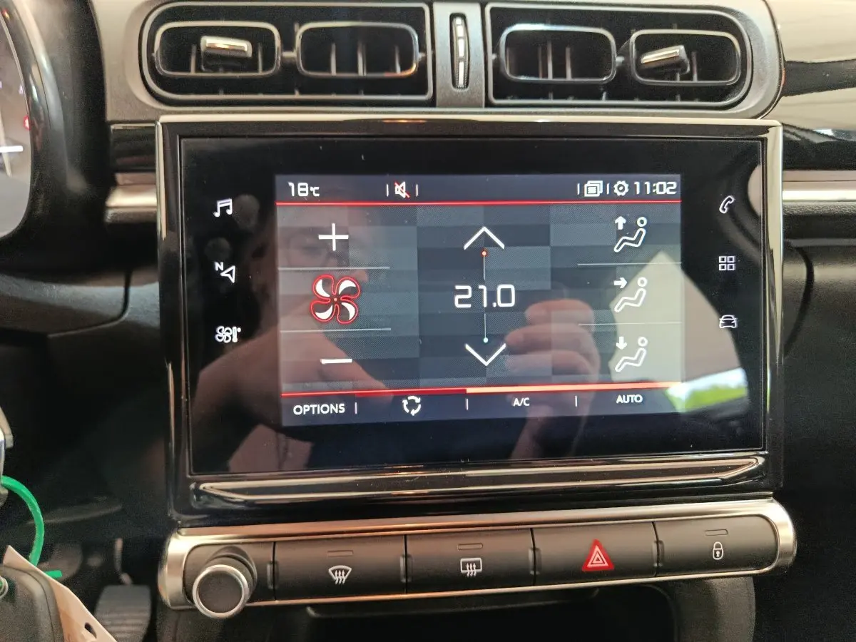 Écran tactile central affichant la climatisation à 21°C dans l'habitacle noir de la Citroën C3 blanche.