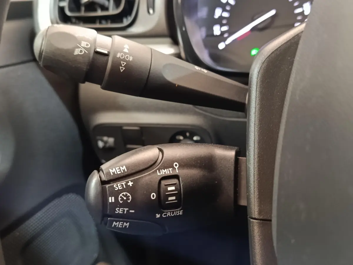 Gros plan sur la commande de régulateur de vitesse côté gauche du volant d'une Citroën C3 blanche 2022.