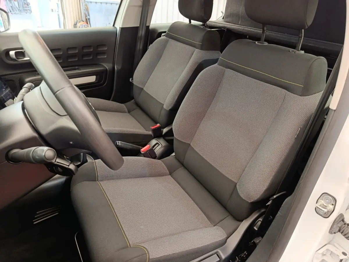 Vue intérieure côté conducteur de la Citroën C3 blanche 2022, sièges tissu gris avec surpiqûres jaunes.