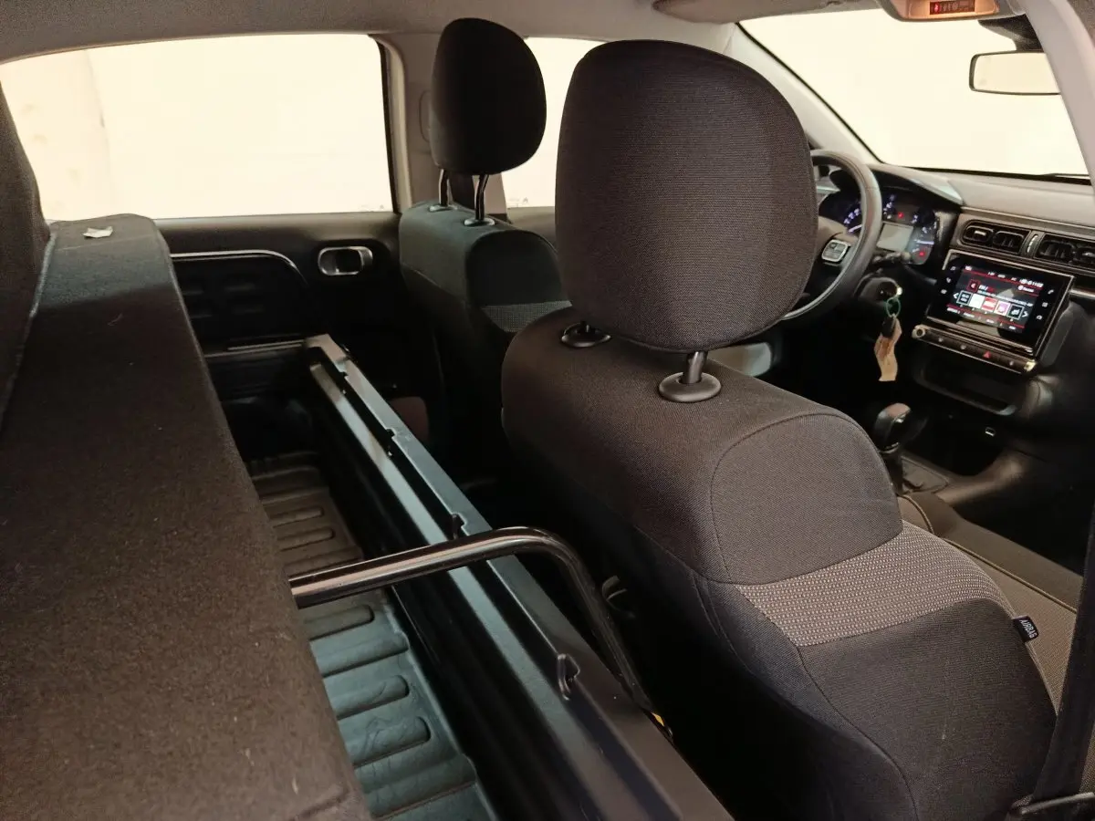 Vue intérieure arrière droite de la Citroën C3 blanche 2022, montrant les sièges noirs et l'écran tactile du tableau de bord.