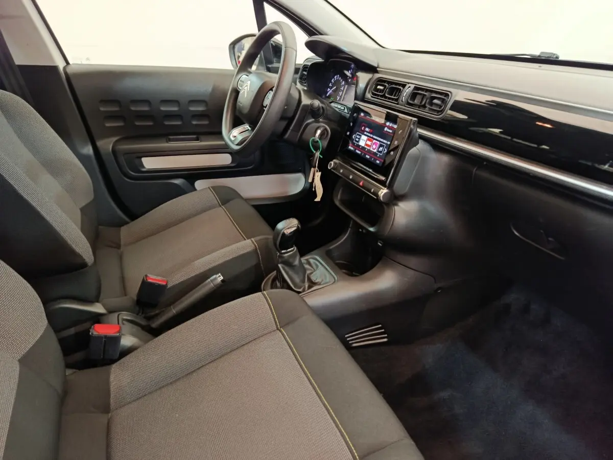 Vue intérieure côté conducteur de la Citroën C3 2022 avec tableau de bord noir, écran tactile et sièges gris.