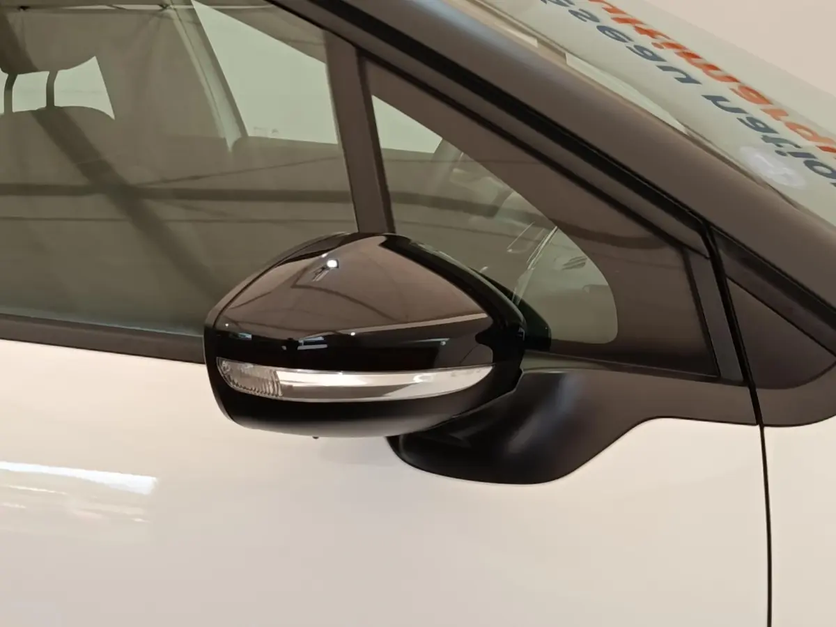 Rétroviseur noir avec clignotant intégré côté conducteur d'une Citroën C3 blanche, vue rapprochée.
