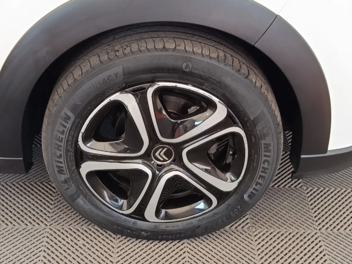 Gros plan sur la roue avant droite d'une Citroën C3 blanche, avec jante alliage noire et argentée au design moderne.