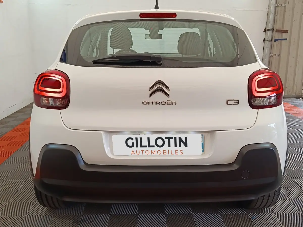 Vue arrière d'une Citroën C3 blanche avec feux arrière LED et pare-chocs noir dans un garage.